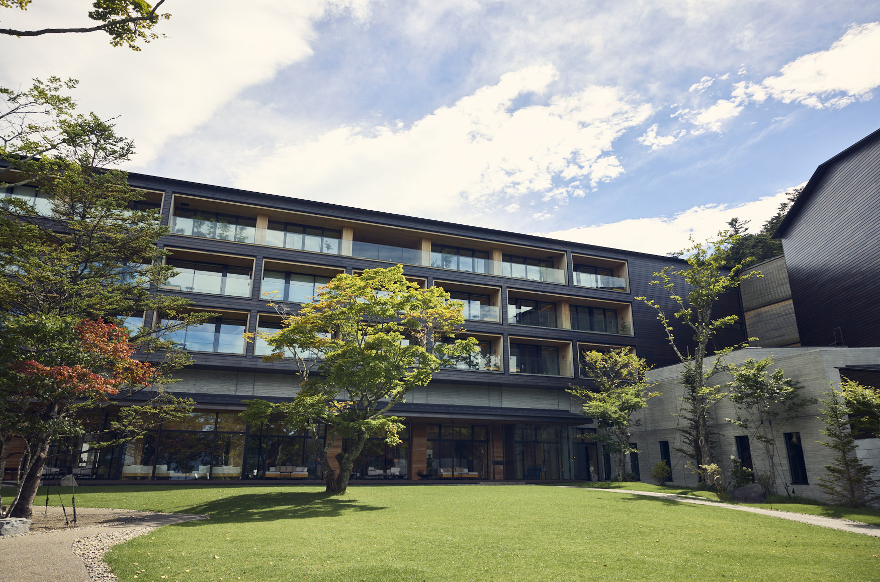 ネイビーのスーツセットアップ・ブラックのニットを着用した、ホテルのフロントでポケットに手を入れて上を見ている男性