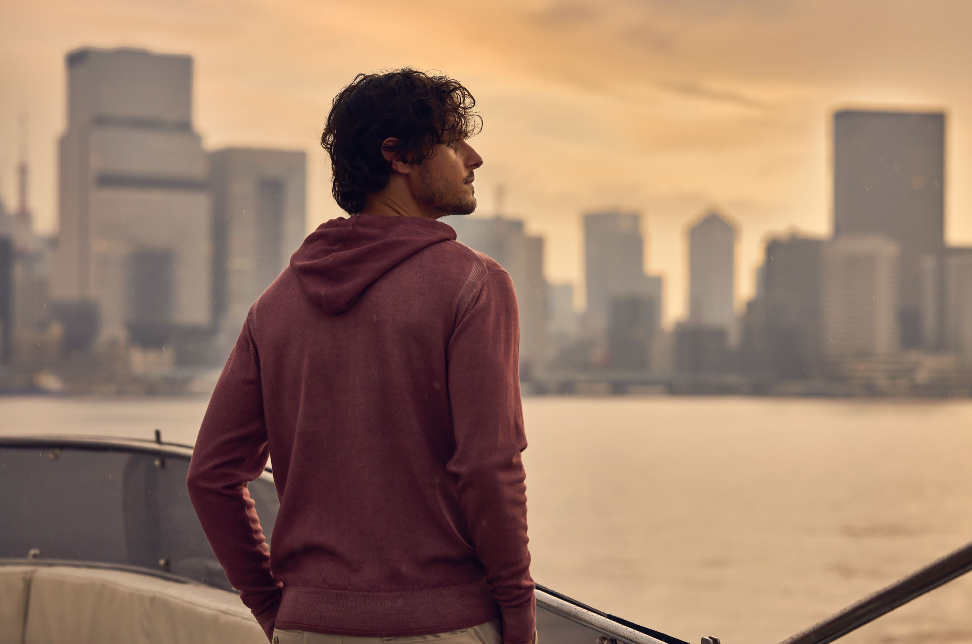 ライトピンクのトップス・ライトベージュのパンツを着用した男性がポケットに手を入れて遠くを見ている様子