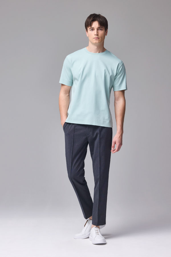水色の半袖Tシャツとネイビーのパンツを着用した男性の正面姿
