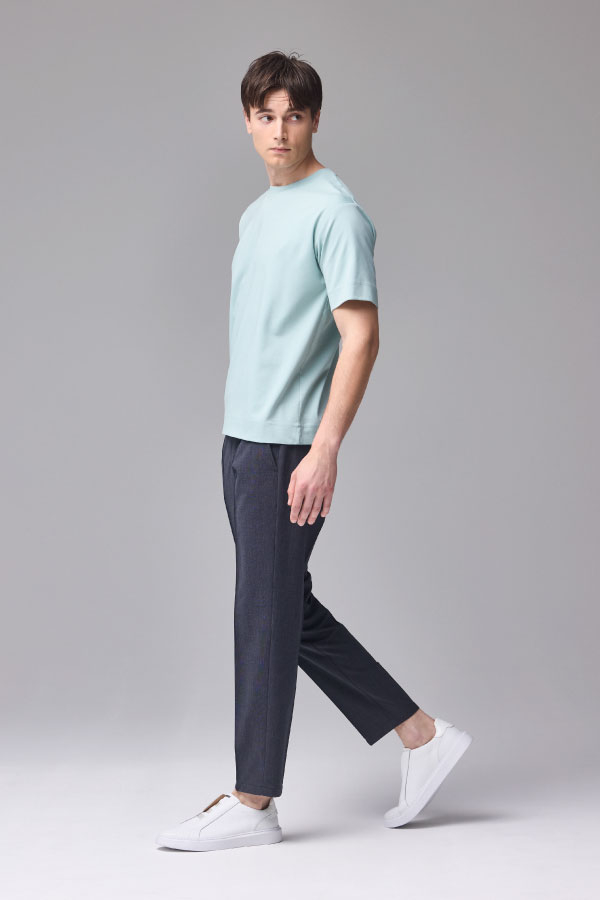 水色の半袖Tシャツとネイビーのパンツを着用した男性の横向き姿