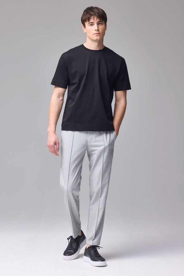 黒の半袖Tシャツとグレーのパンツを着用した男性の正面姿