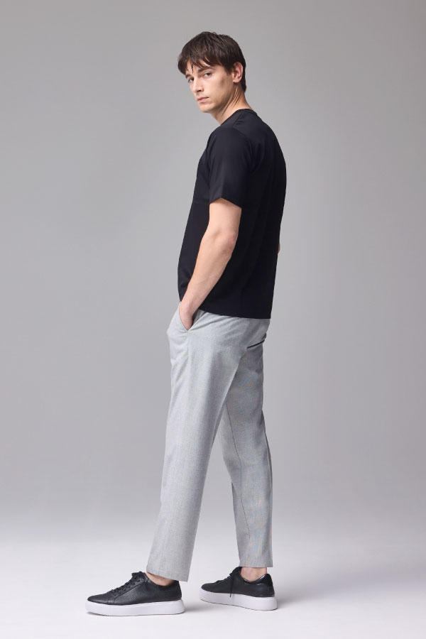 黒の半袖Tシャツとグレーのパンツを着用した男性の横向き姿