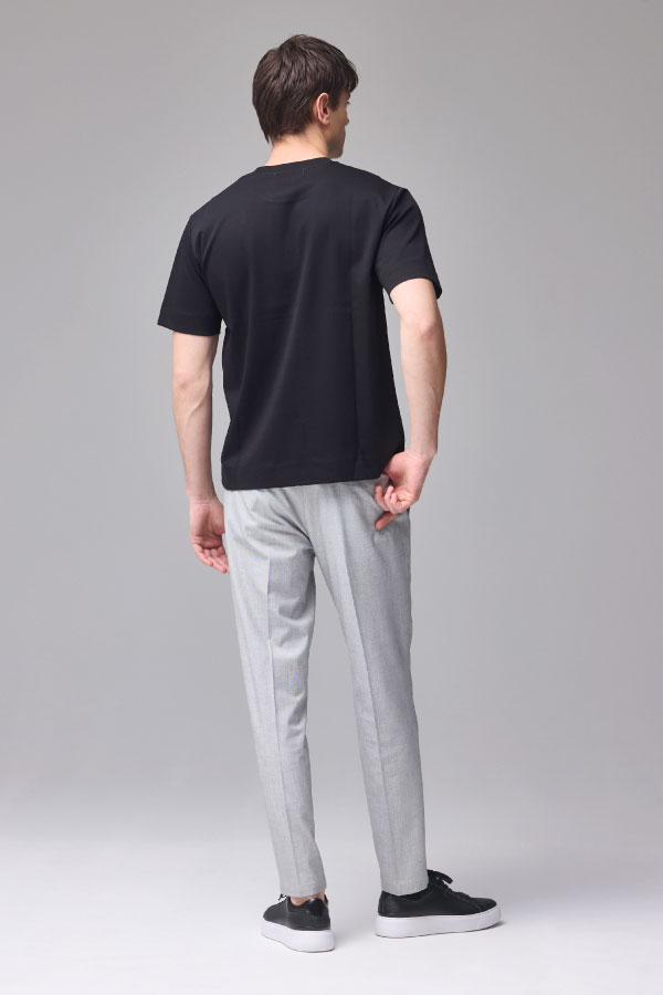 黒の半袖Tシャツとグレーのパンツを着用した男性の後ろ姿