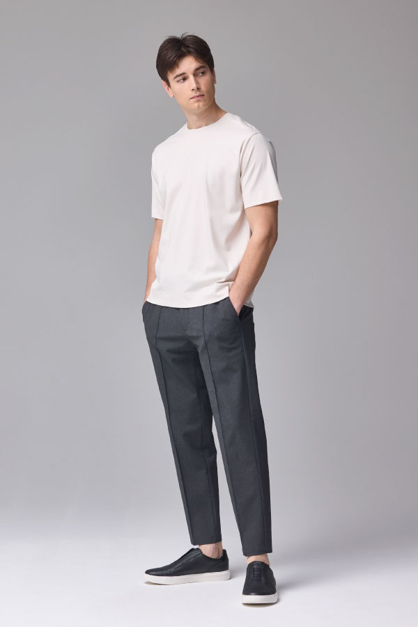白の半袖Tシャツとダークグレーのパンツを着用した男性の正面姿