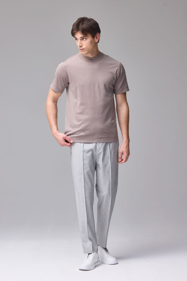 ブラウンの半袖Tシャツとライトグレーのパンツを着用した男性の正面姿