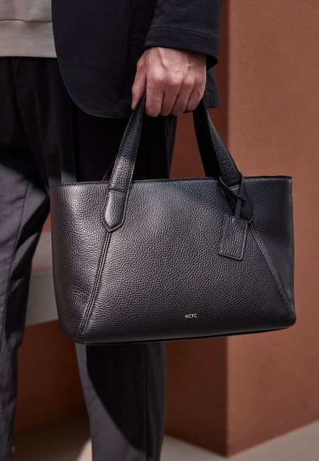 MCFC MINI TOTE BAG ブラックを持つ着用イメージ